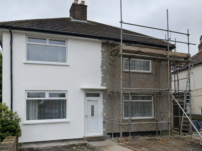 A 1950s semi-detached house with new white render on one half and old pebble dash still showing on the other